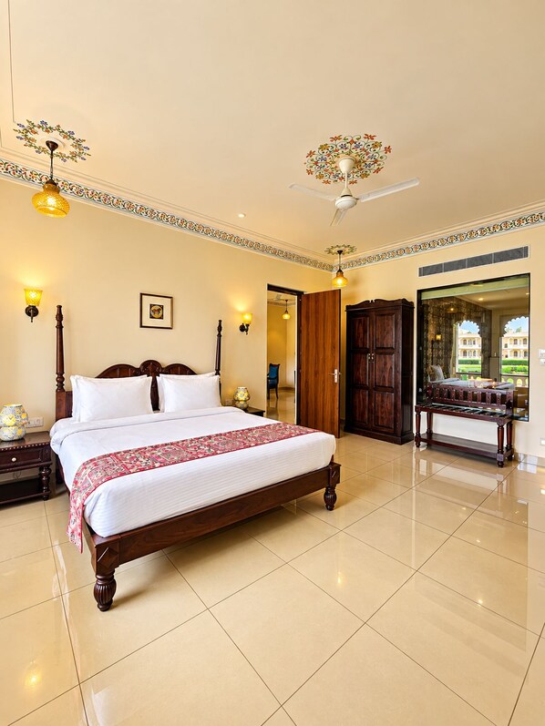 A spacious bedroom with a large bed, a ceiling fan, and a view of a building through a glass door.