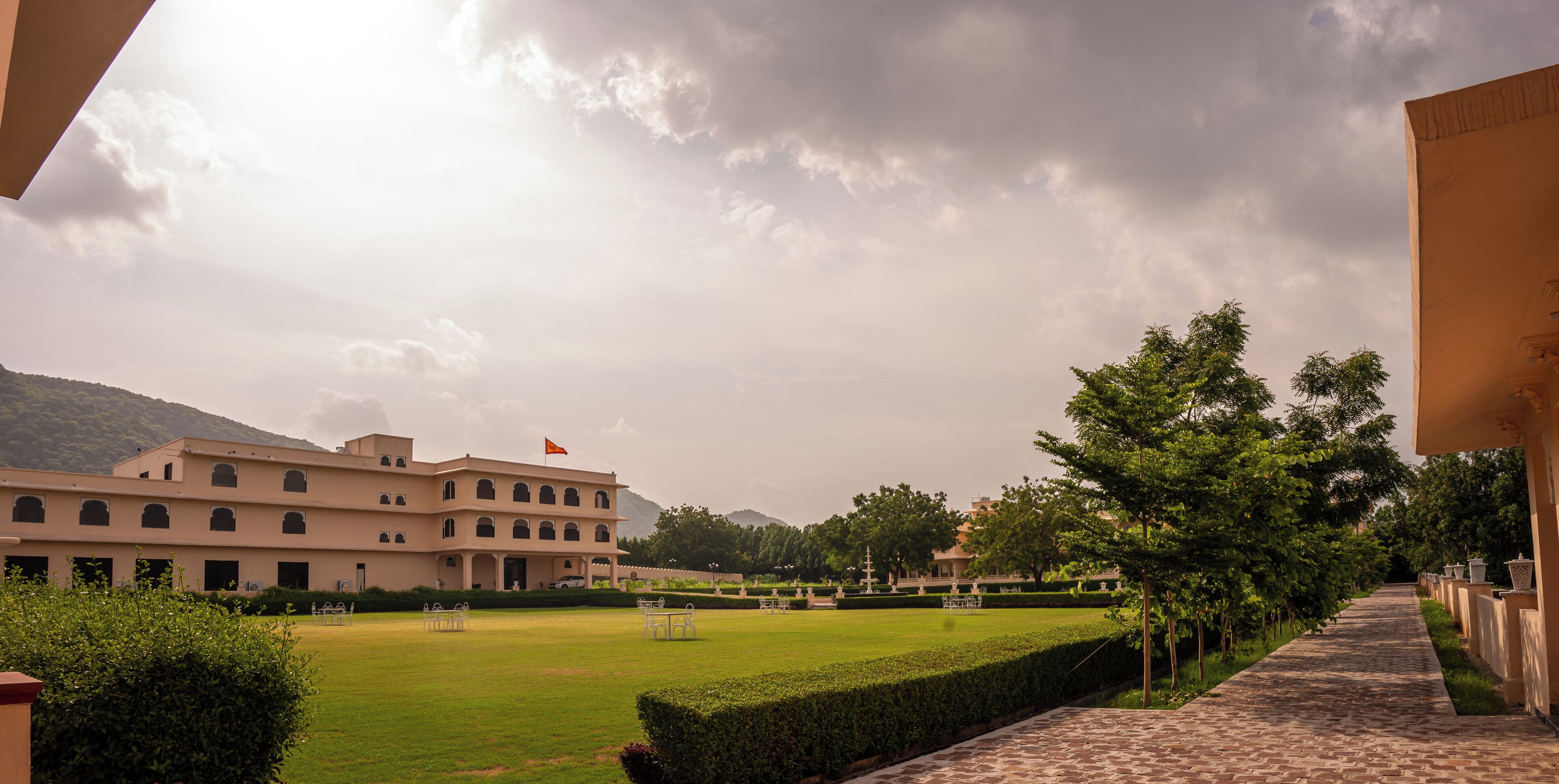 A large building with a flag, a well-maintained lawn, and a pathway.
