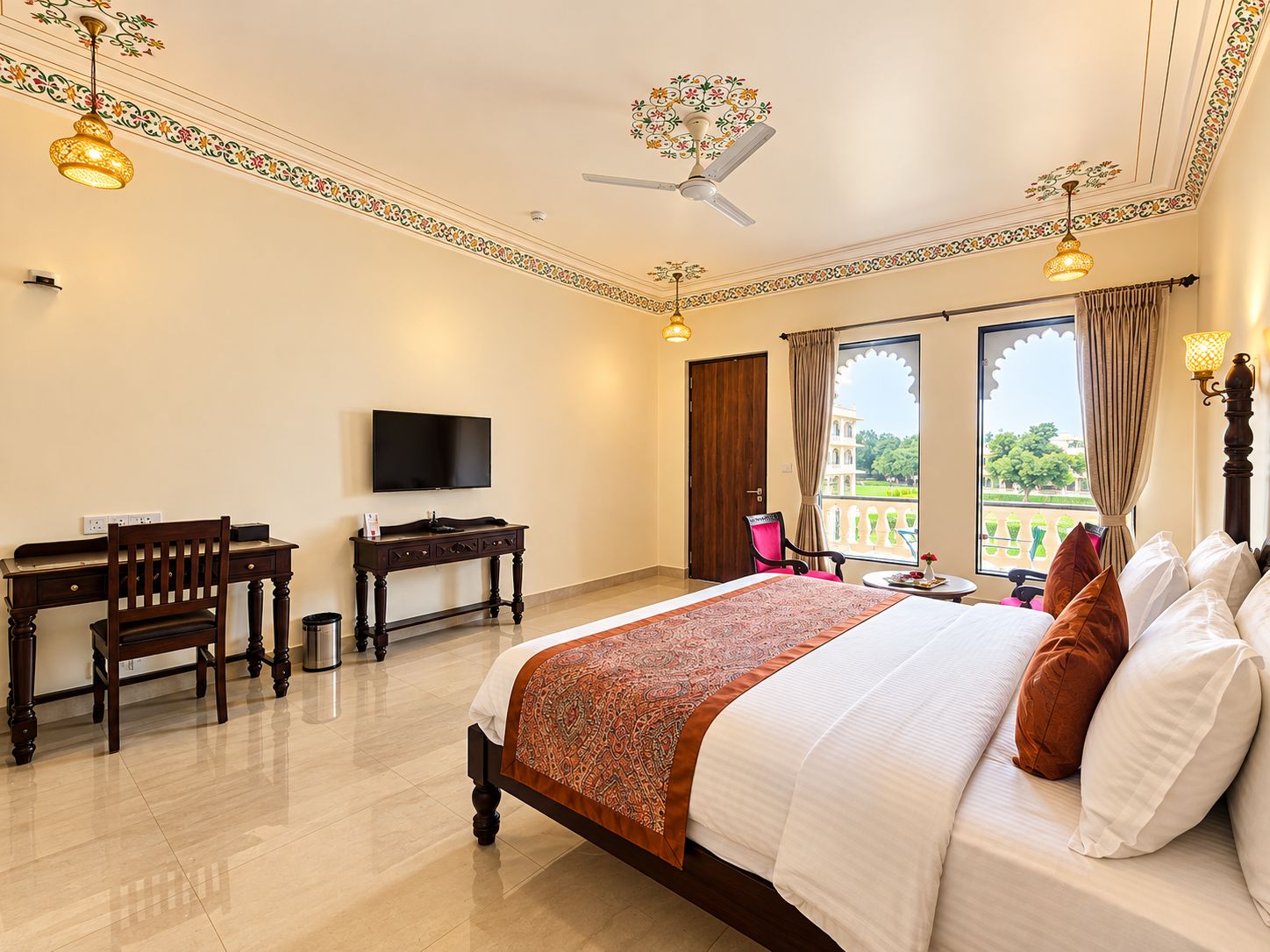 Quarto de hotel com cama, escrivaninha, televisão e vista para a varanda.