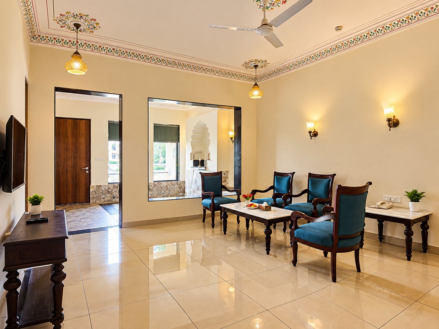 Um hall de hotel com área de estar, ventilador de teto e arandelas decorativas.