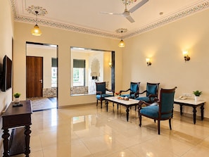 A hotel lobby with a seating area, a ceiling fan, and decorative wall sconces. - Trulyy The Shakti Vilas (Udaipur)
