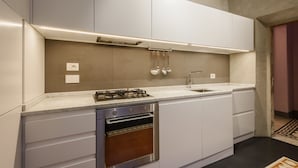 Une cuisine moderne avec des meubles blancs, une cuisinière à gaz, un four et un évier.