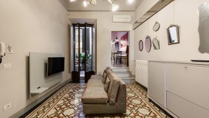 Un salon moderne avec un canapé, un téléviseur, un sol à motifs et un escalier menant à une autre pièce.