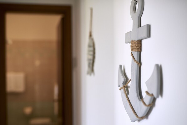 A white anchor decoration with a rope, hanging on a wall.