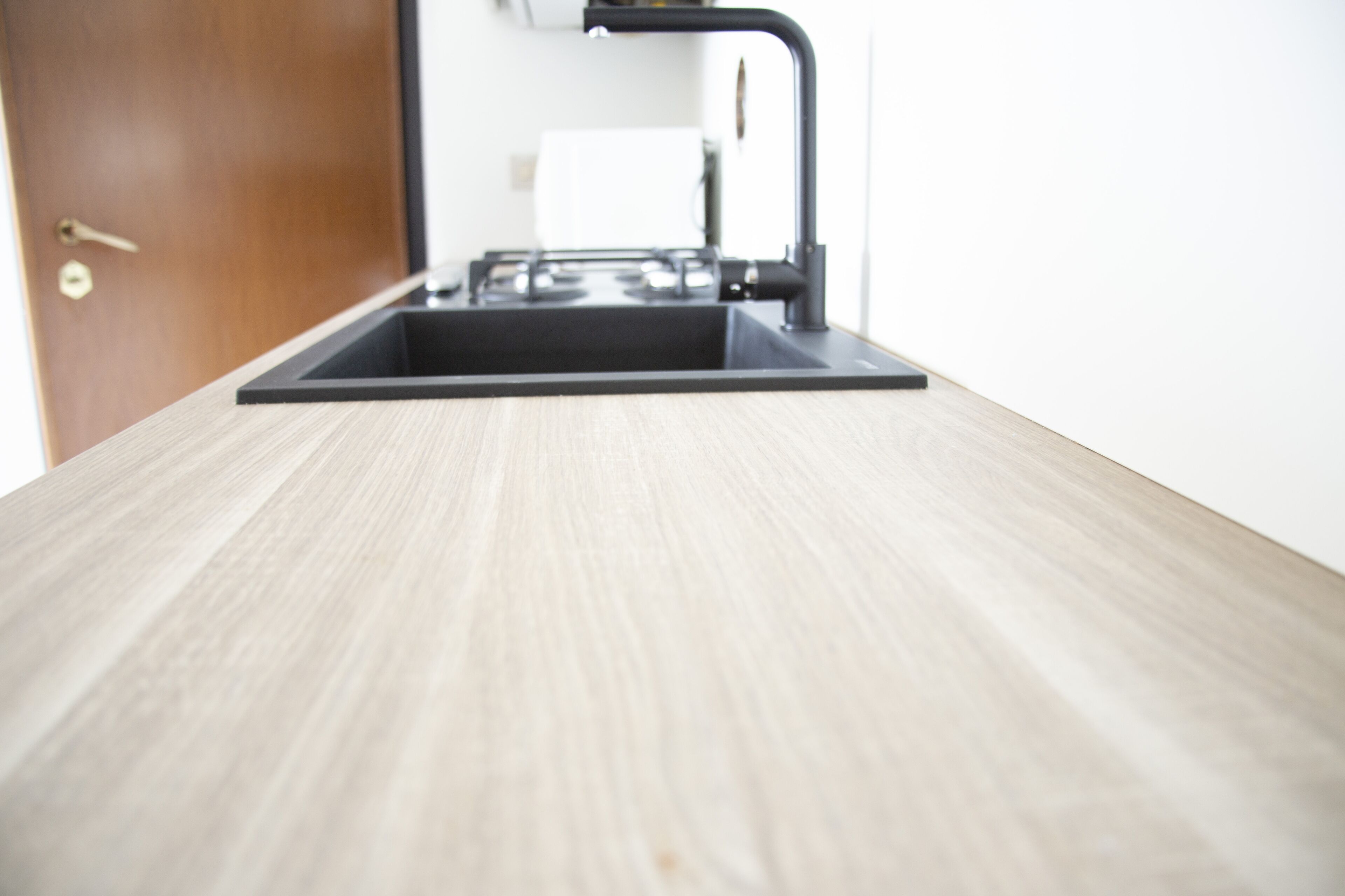 Een keuken met een zwarte spoelbak en een houten aanrecht.