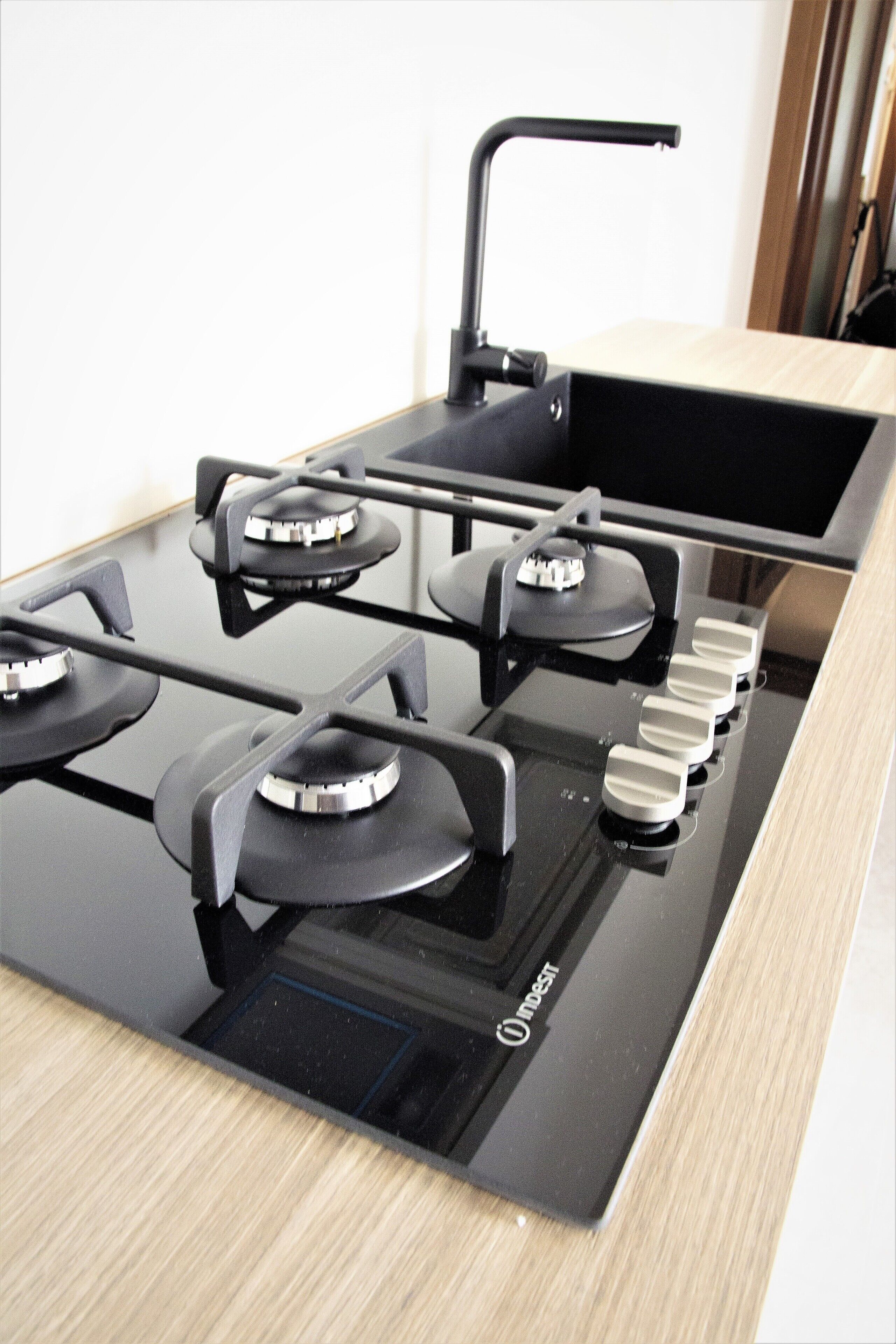 A modern kitchen with a black stove top, four burners, and a range hood.