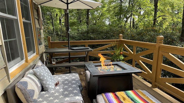 Eine Terrasss mit Feuerstelle, Sitzgruppe und Tisch.