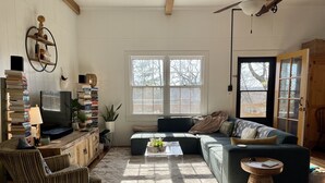 Ein Wohnzimmer mit einer Couch, einem Couchtisch, einem Fernseher und Bücherregalen.