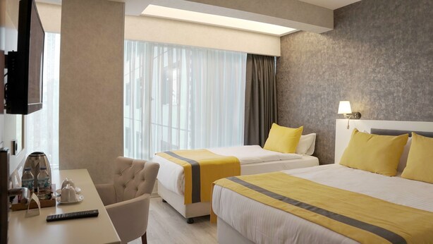 A hotel room with two beds, a desk with a coffee maker, a TV, and a large window with curtains. - Resun Hotel Ankara (Ankara)
