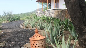 A house with a stone foundation, a wooden porch, and a view of a hill. - La Fora Ecolodge (São Filipe)