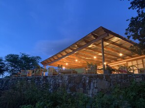 En modern byggnad med en mur av natursten, ett trädäck och en utomhusplats med sittmöbler.