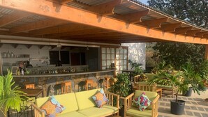An outdoor seating area with wooden furniture, a bar, and potted plants. - La Fora Ecolodge (São Filipe)