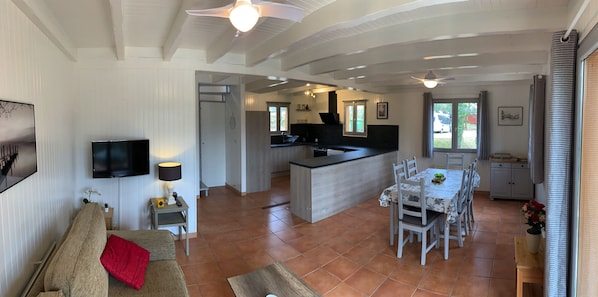 A spacious living area with a sofa, a dining table, and a kitchen in the background.