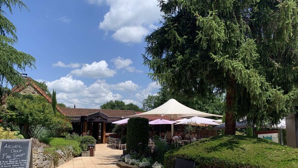 Ein Golfproshop und Restaurant mit Außenbereich, umgeben von viel Grün und blauem Himmel.
