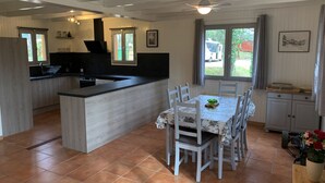 Eine Küche mit Kochinsel, Esstisch mit Stühlen und einem Fenster mit Vorhängen.