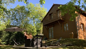 Eine Holzhütte mit einer Veranda, einem Grill und einem Sonnenschirm.