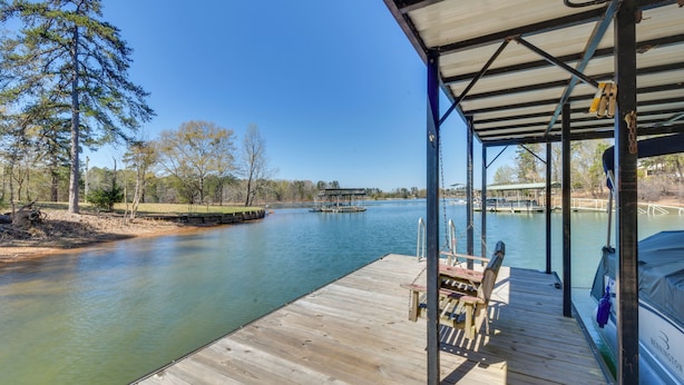 A wooden dock with a covered seating area overlooking a calm river.