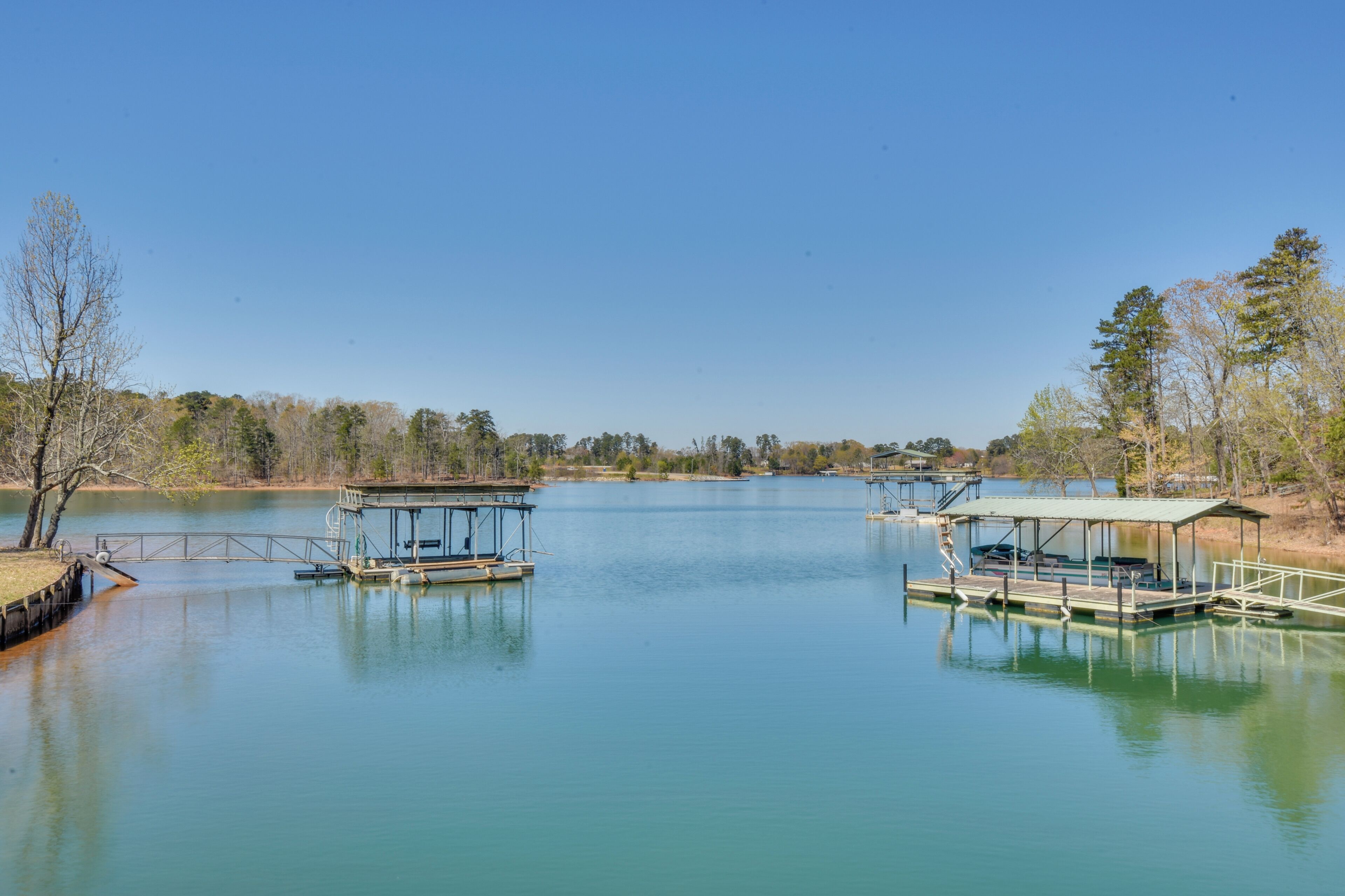 A calm lake with two docked boats and a covered seating area.