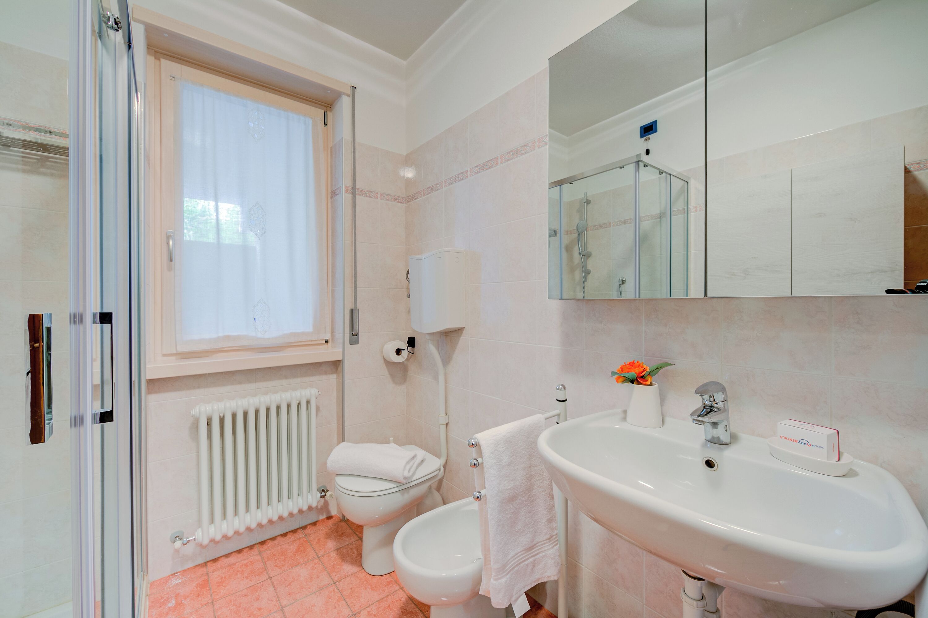 A bathroom with a toilet, bidet, sink, and a large mirror.