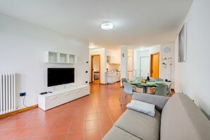 Een moderne woonkamer met een flatscreen televisie, een witte tv-kast en een bank.