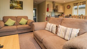 A living room with two sofas, a coffee table, and a kitchen in the background. - Oak Lodge (Preston)
