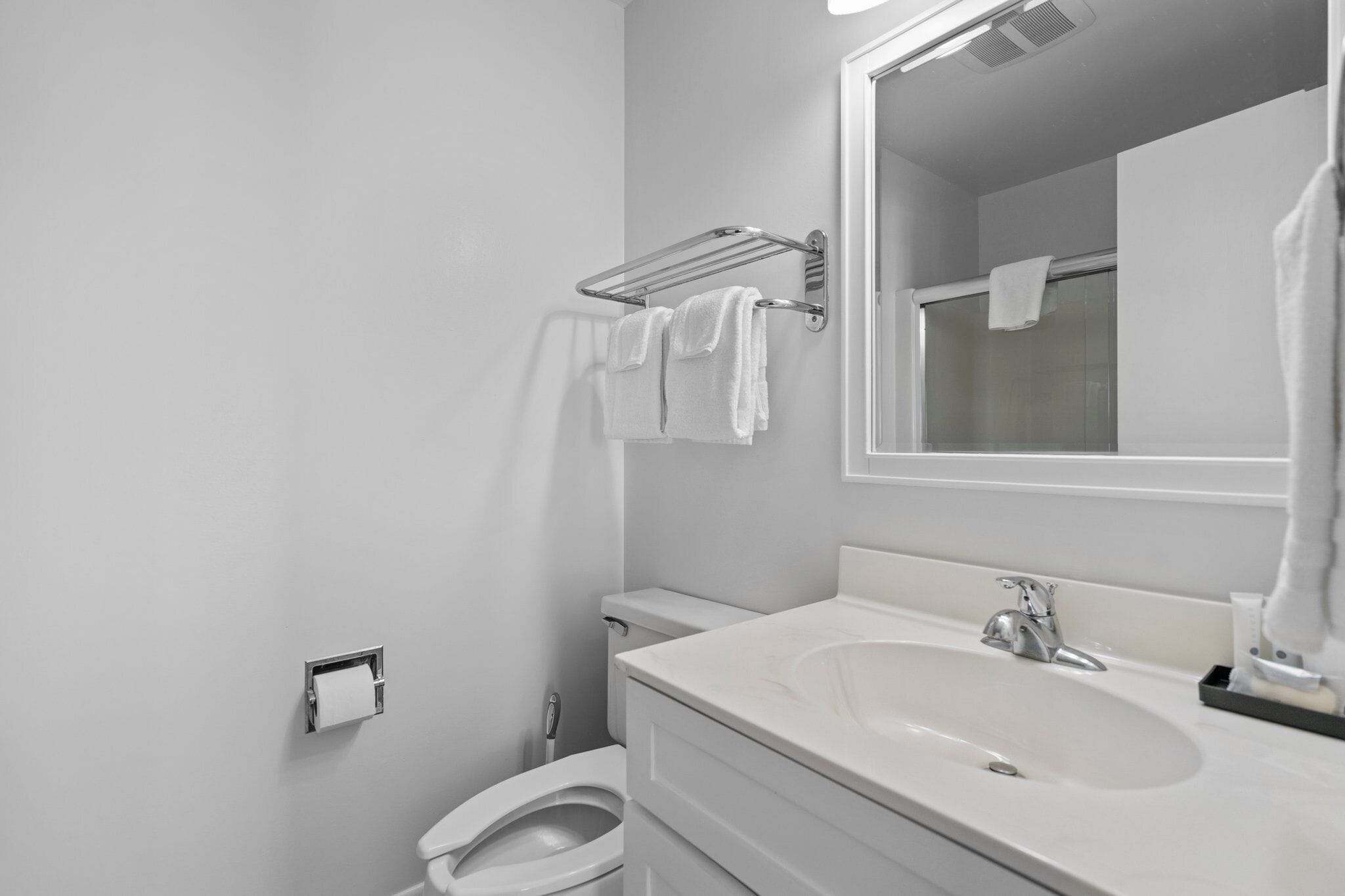 Une salle de bain moderne avec un lavabo blanc, un miroir et un porte-serviettes.