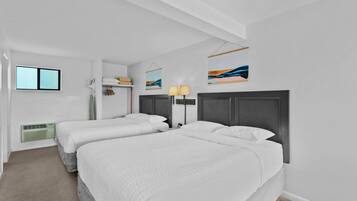 Habitació d'hotel moderna amb dos llits individuals, una finestra gran, un calefactor fixat a la paret i obra d'art.