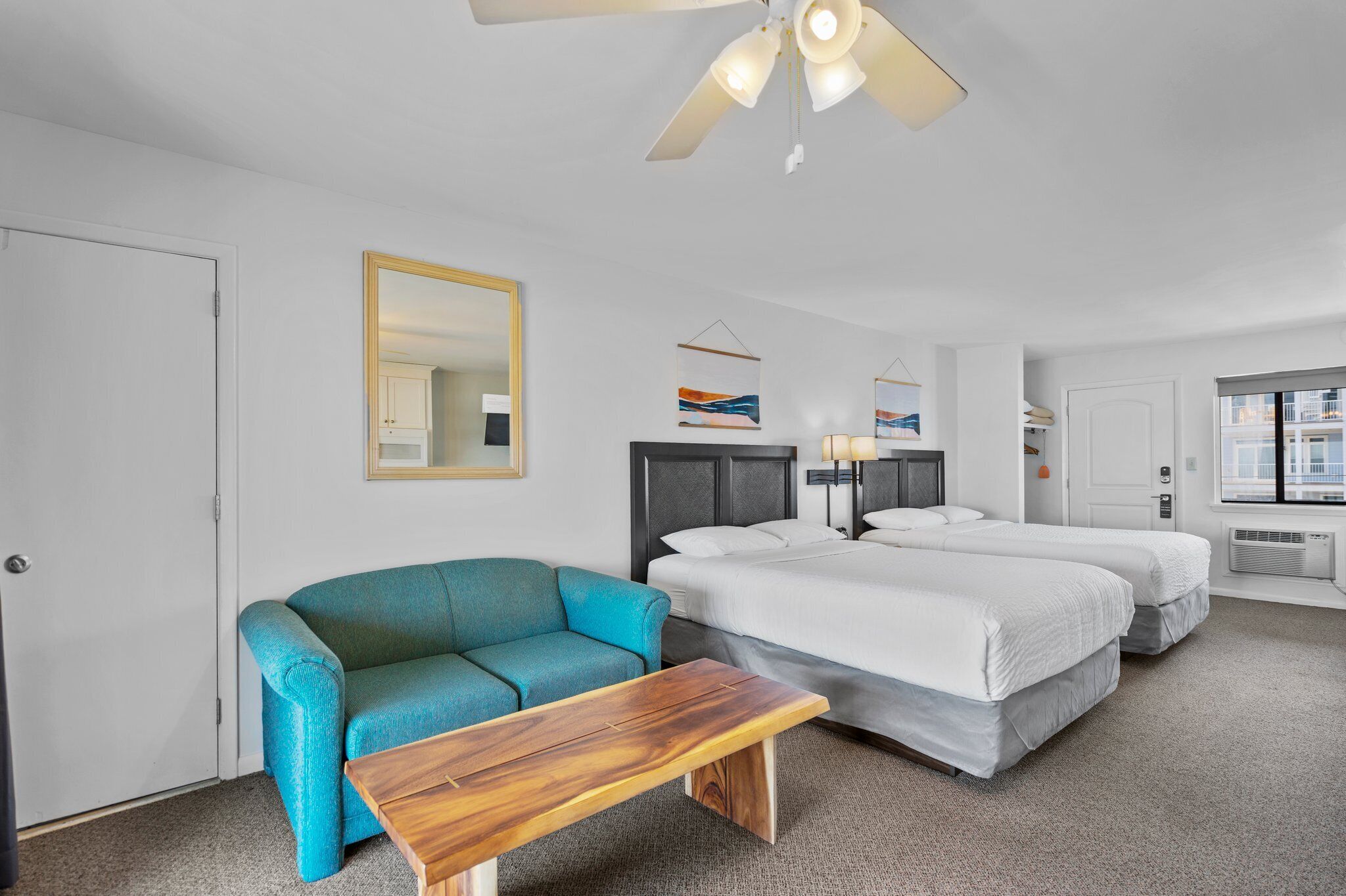 Una habitación de hotel con una cama, un sofá, una mesa de madera y un ventilador de techo.