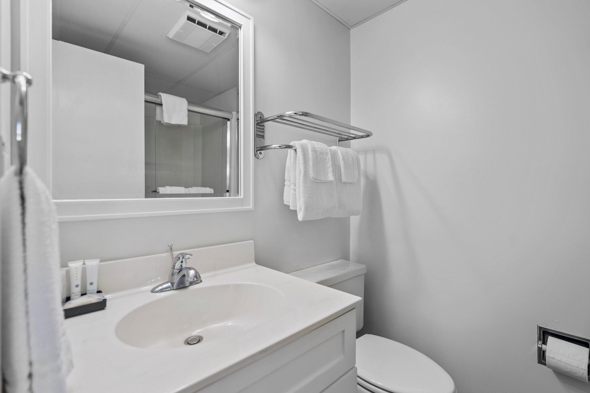 Une salle de bain moderne avec un lavabo blanc, un miroir et un porte-serviettes.