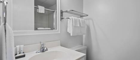 Une salle de bain moderne avec un lavabo blanc, un miroir et un porte-serviettes.