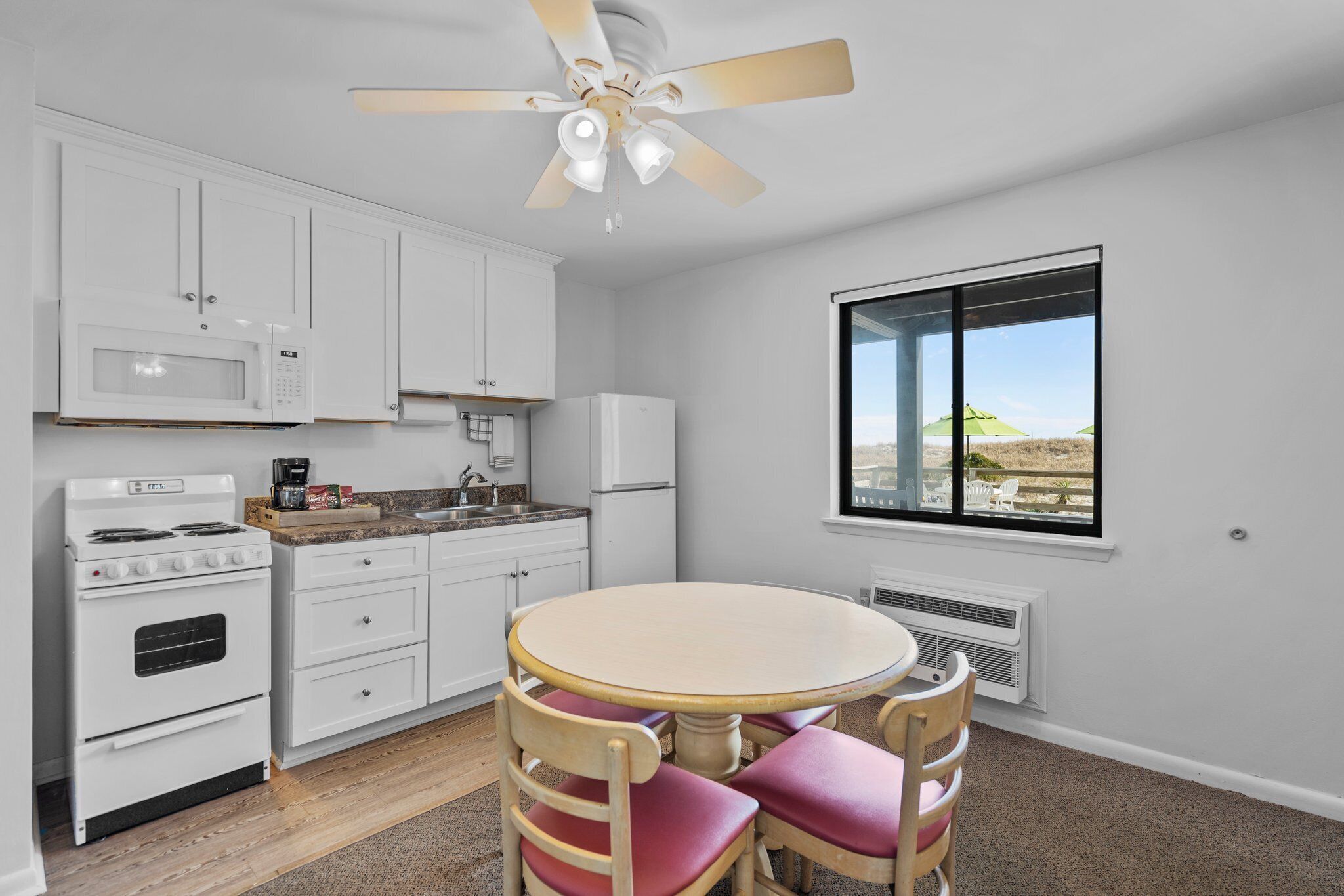 A kitchen with white cabinets, a stove, microwave, and a dining table with chairs.