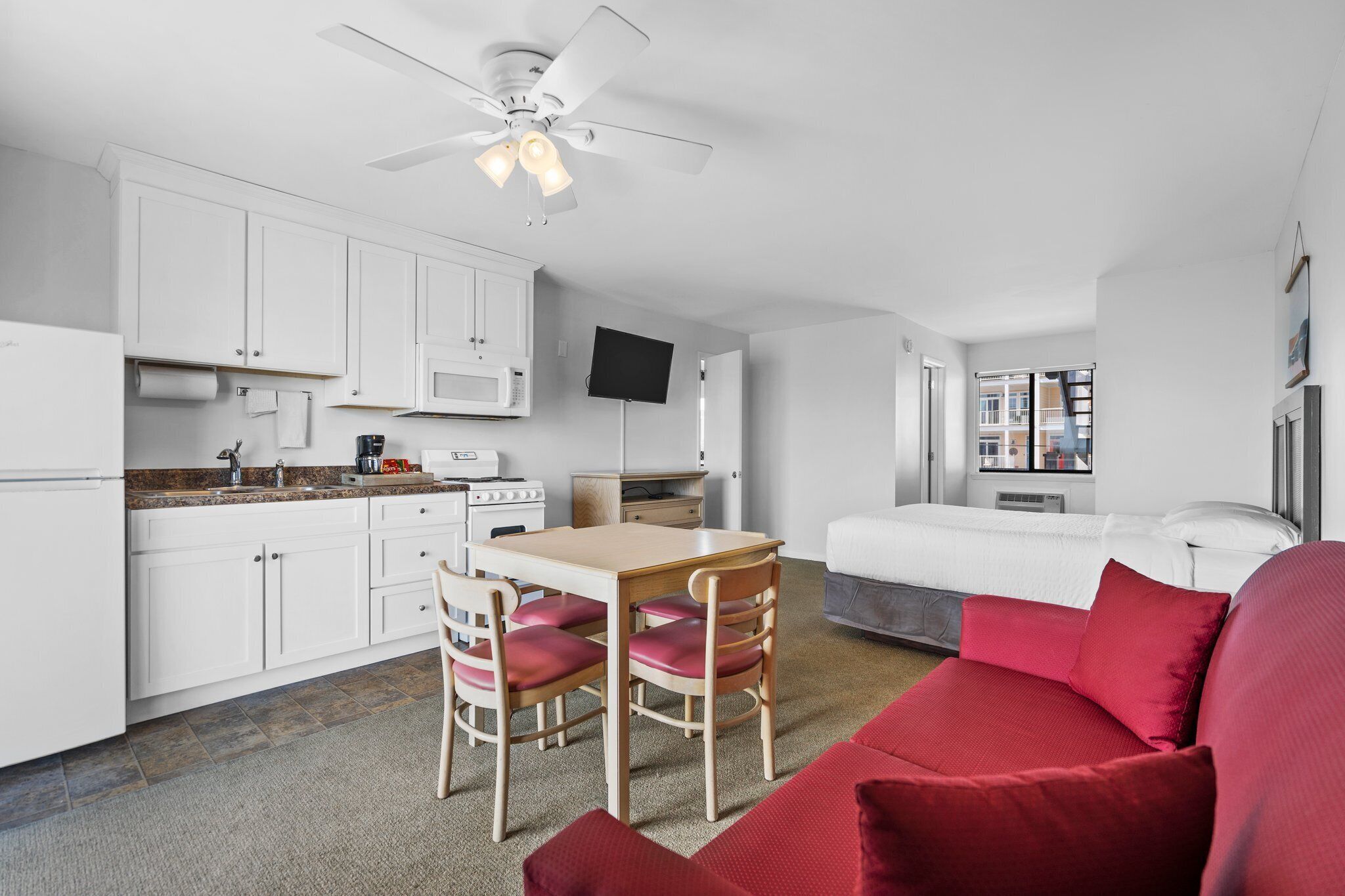 A compact kitchen with white cabinets, a microwave, and a dining area with a table and chairs.