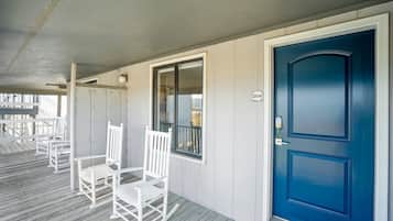 A covered porch with white rocking chairs and a blue door.