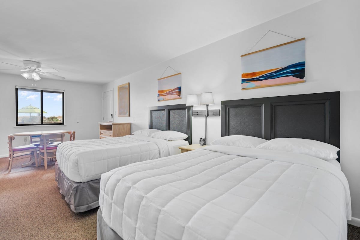 A hotel room with two beds, a desk, and a chair.