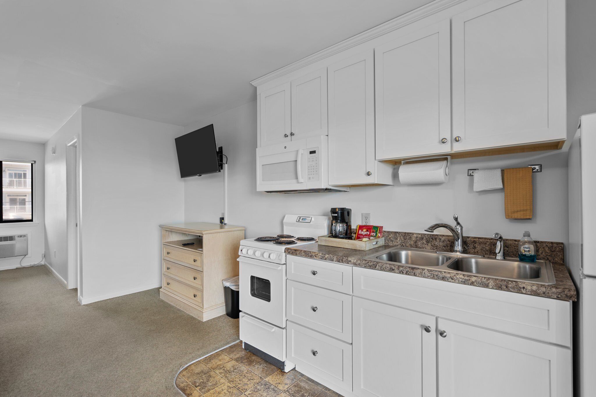 Une cuisine moderne avec des meubles blancs, un four à micro-ondes encastré, une cuisinière et un évier.