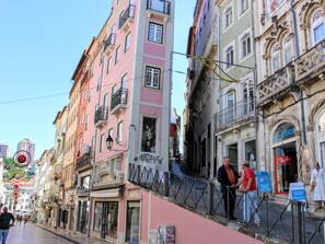 A street with colorful buildings, a man talking to another person, and a dental clinic sign. - Entre Ruas Apartments (Coimbra)