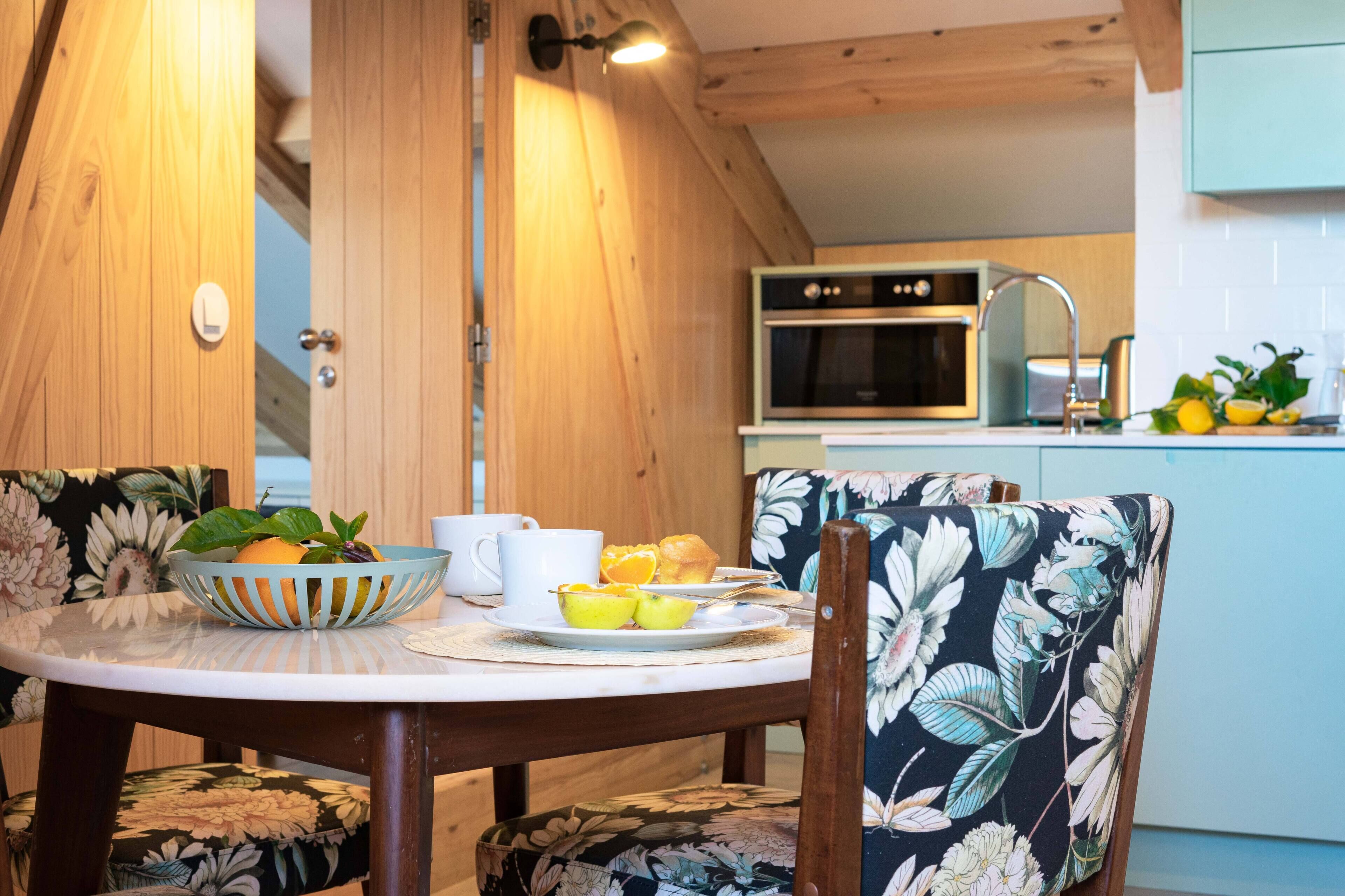 A wooden interior with a dining table set for breakfast, including fruits and a muffin.