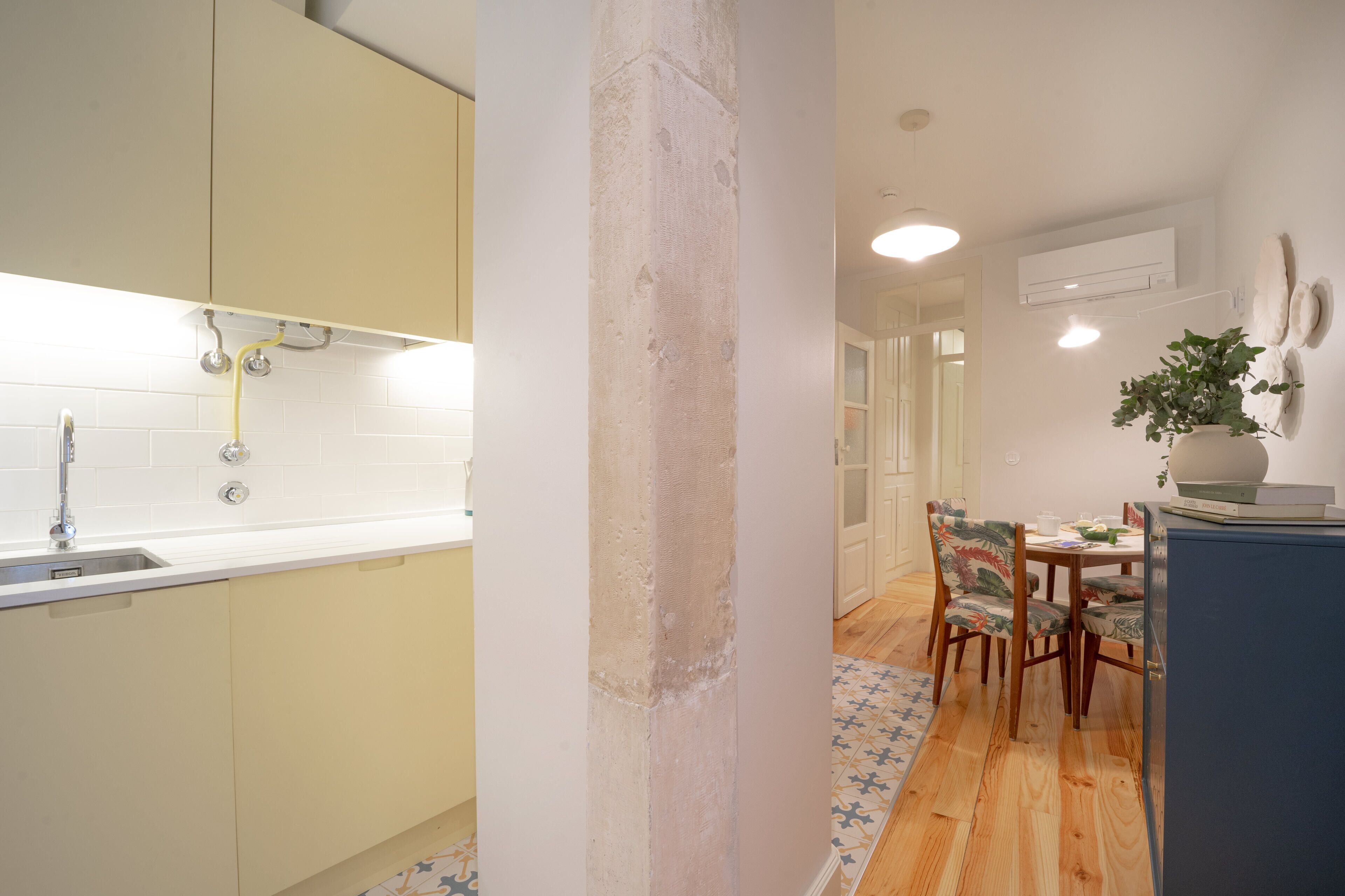A kitchen with a sink, cabinets, and a dining area with chairs and a table.