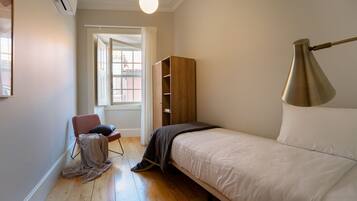 Un dormitorio con una cama, una silla, un armario y una lámpara.