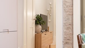 Un passadís amb un armari de fusta, una planta en test i un llum de paret.