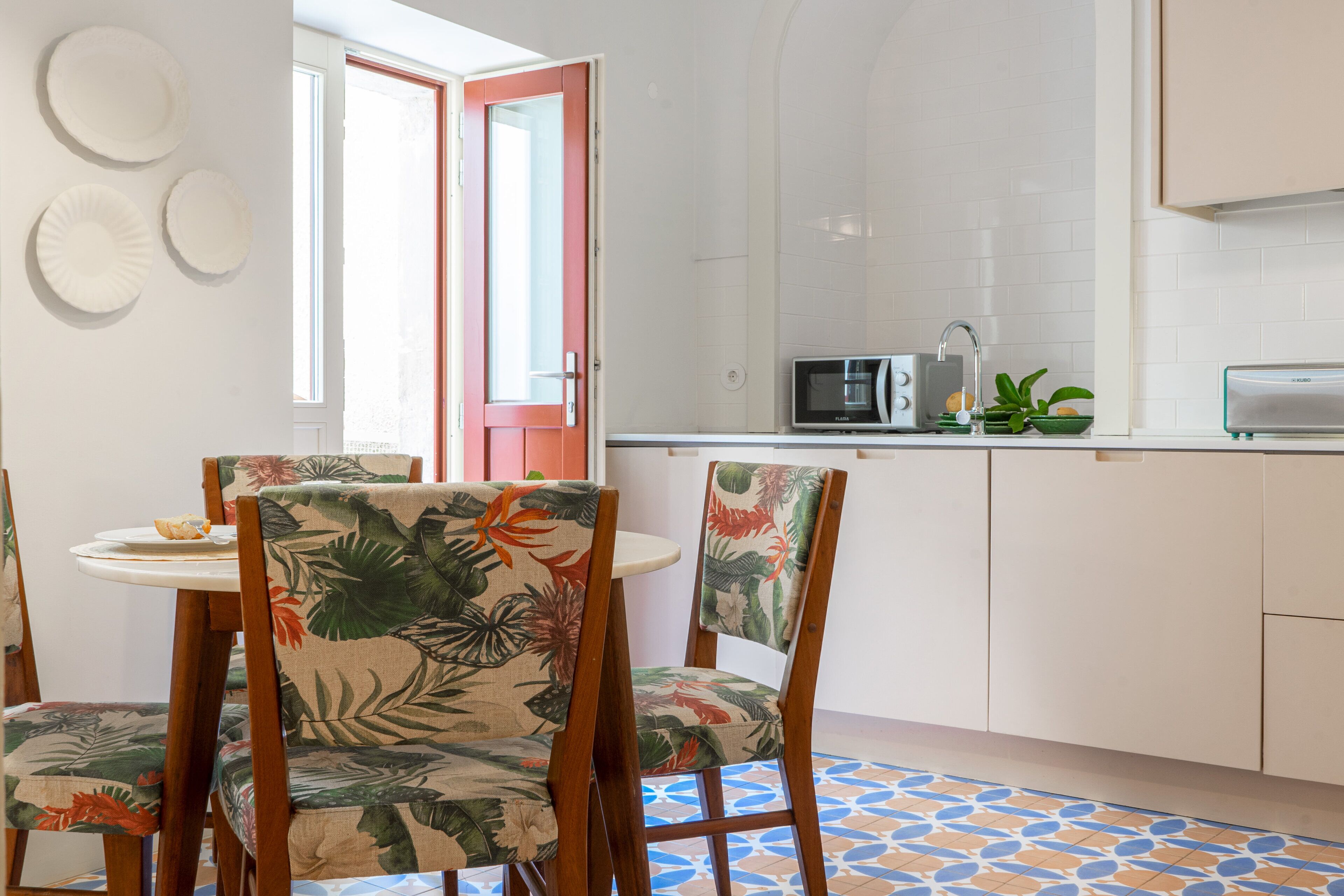 A kitchen with white cabinets, a microwave, and a small dining area with two chairs and a table.