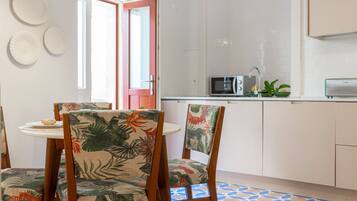 A kitchen with white cabinets, a microwave, and a small dining area with two chairs and a table.