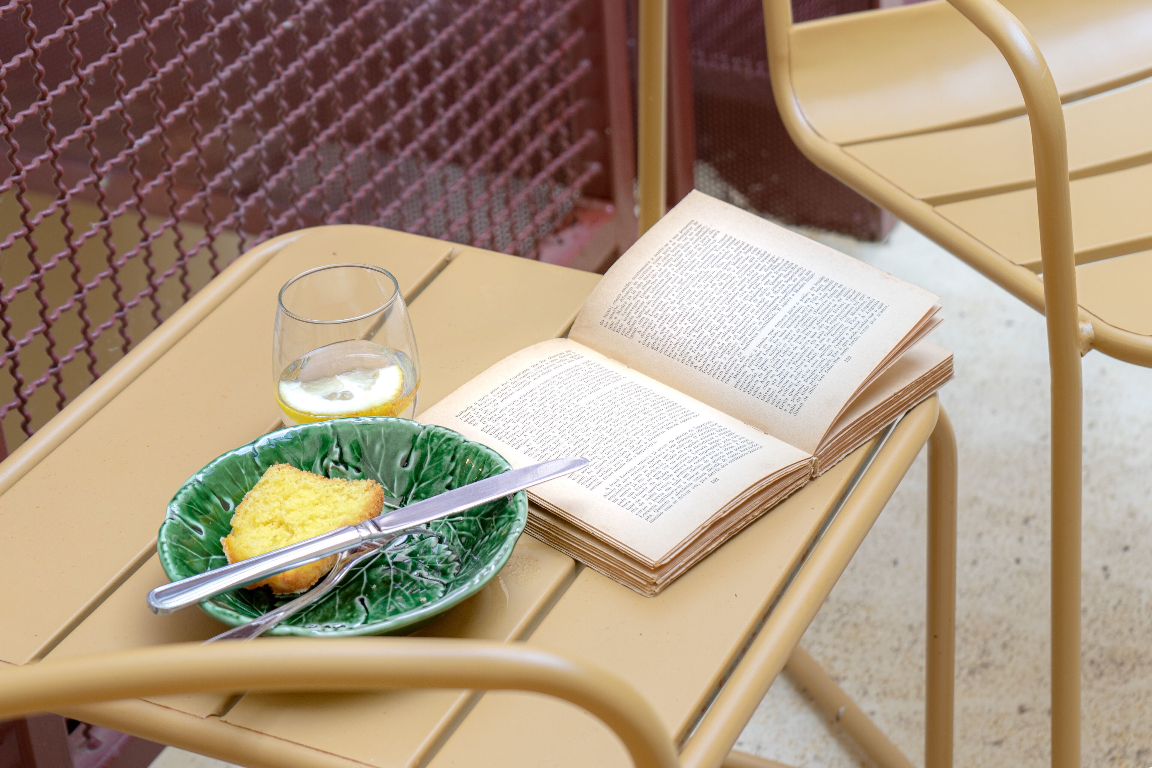A metal table with a book, a glass of water, and a bowl of food.