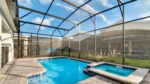 Une piscine entourée de parois en verre, un jacuzzi et une terrasse en briques.