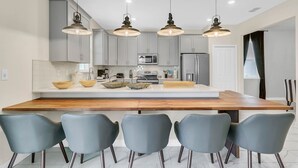 Cozinha moderna com ilha central, armários cinza e iluminação pendente.