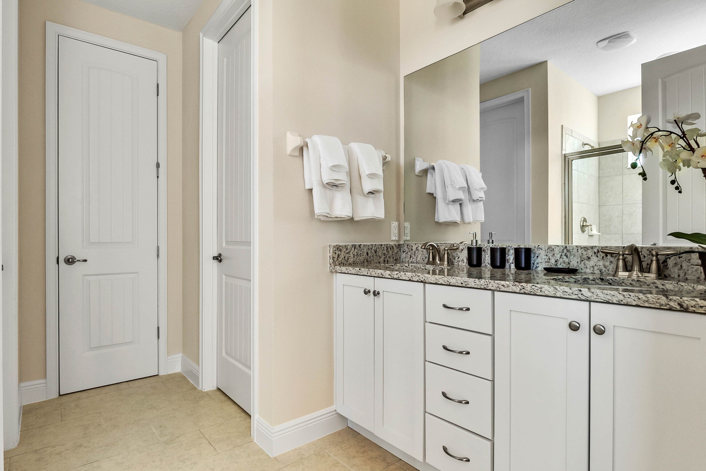 A bathroom with white cabinets, a granite countertop, and a large mirror.