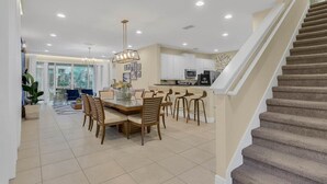 A spacious kitchen with a dining area, a staircase, and a view of the city. - Last Minute Disney! Private Pool, Hot Tub, Game Room & Themed Bedrooms. Book Now! #65729 (Orlando)
