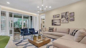 A modern living room with a sofa, chairs, a coffee table, and artwork on the wall. - Last Minute Disney! Private Pool, Hot Tub, Game Room & Themed Bedrooms. Book Now! #65729 (Orlando)