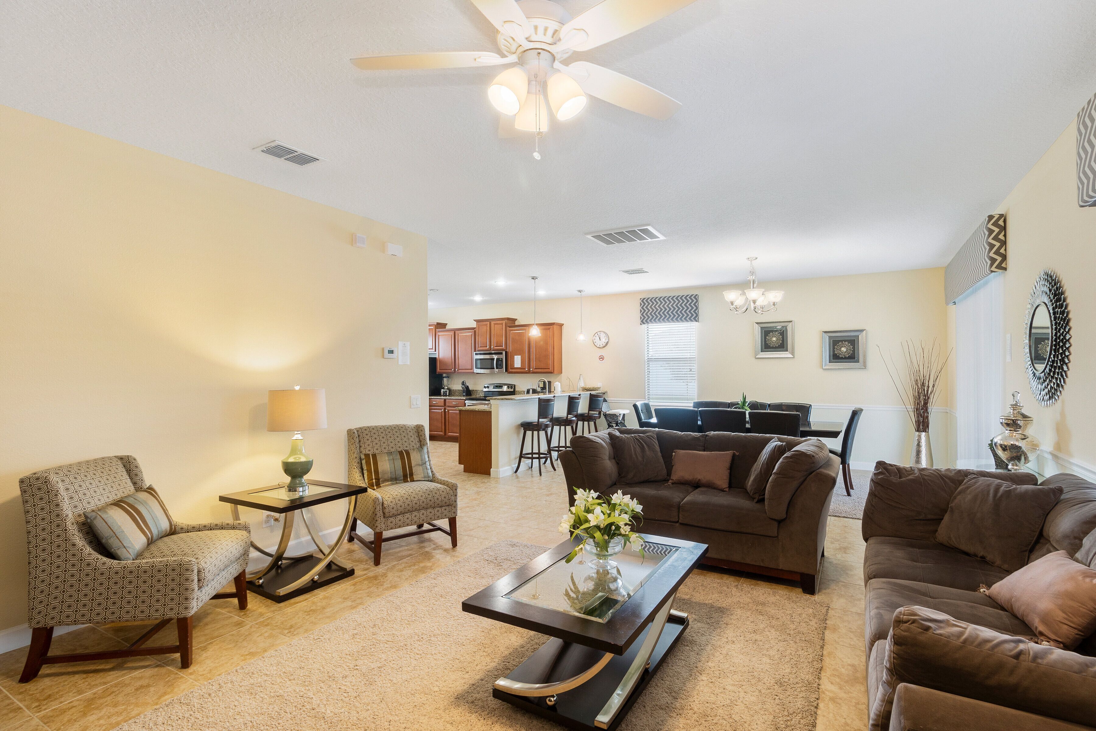 A living room with a sofa, armchairs, a coffee table, and a dining area in the background.