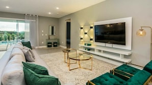 A modern living room with a large flat-screen TV, a sofa, and a coffee table.